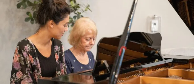 Two women sitting at a grand piano | Aspen Creek Senior Living