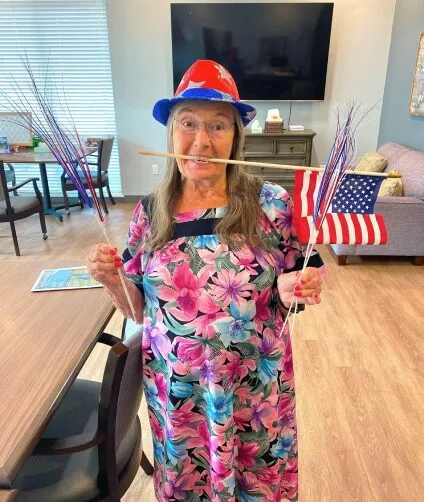 Resident celebrating July 4th with sparklers and a flag | Aspen Creek Senior Living