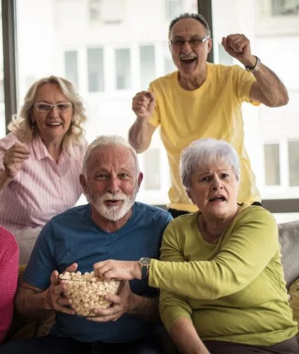 Group of seniors watching a movie and eating popcorn | Aspen Creek Senior Living